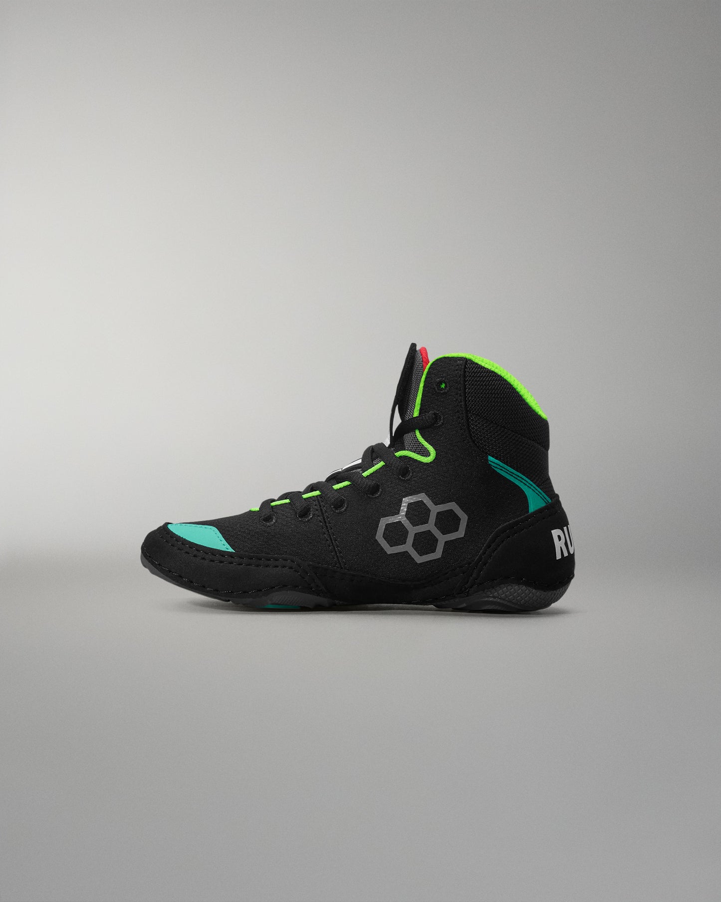 Black wrestling shoe with green accents on a gray background
