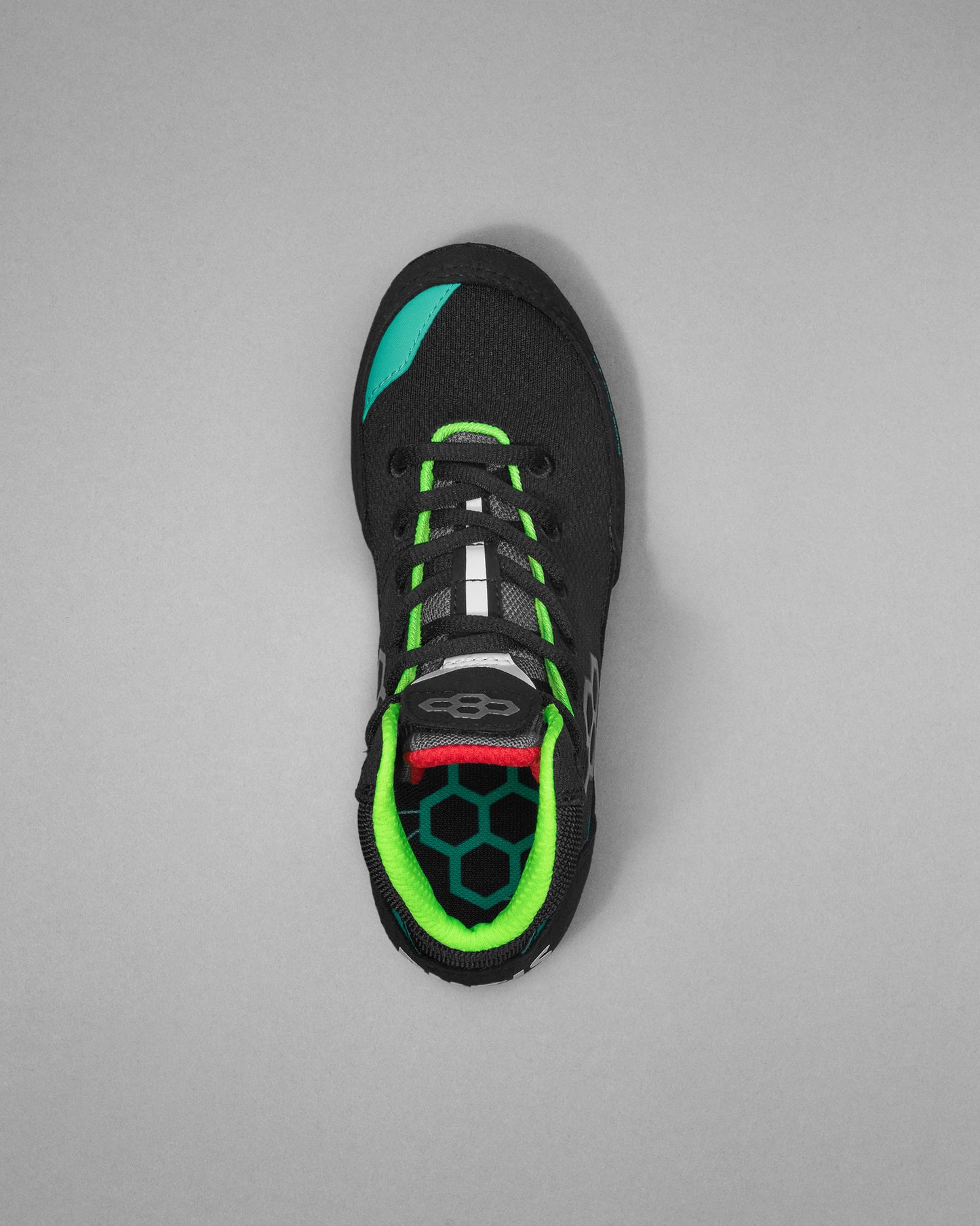 Black wrestling shoe with green accents on a gray background