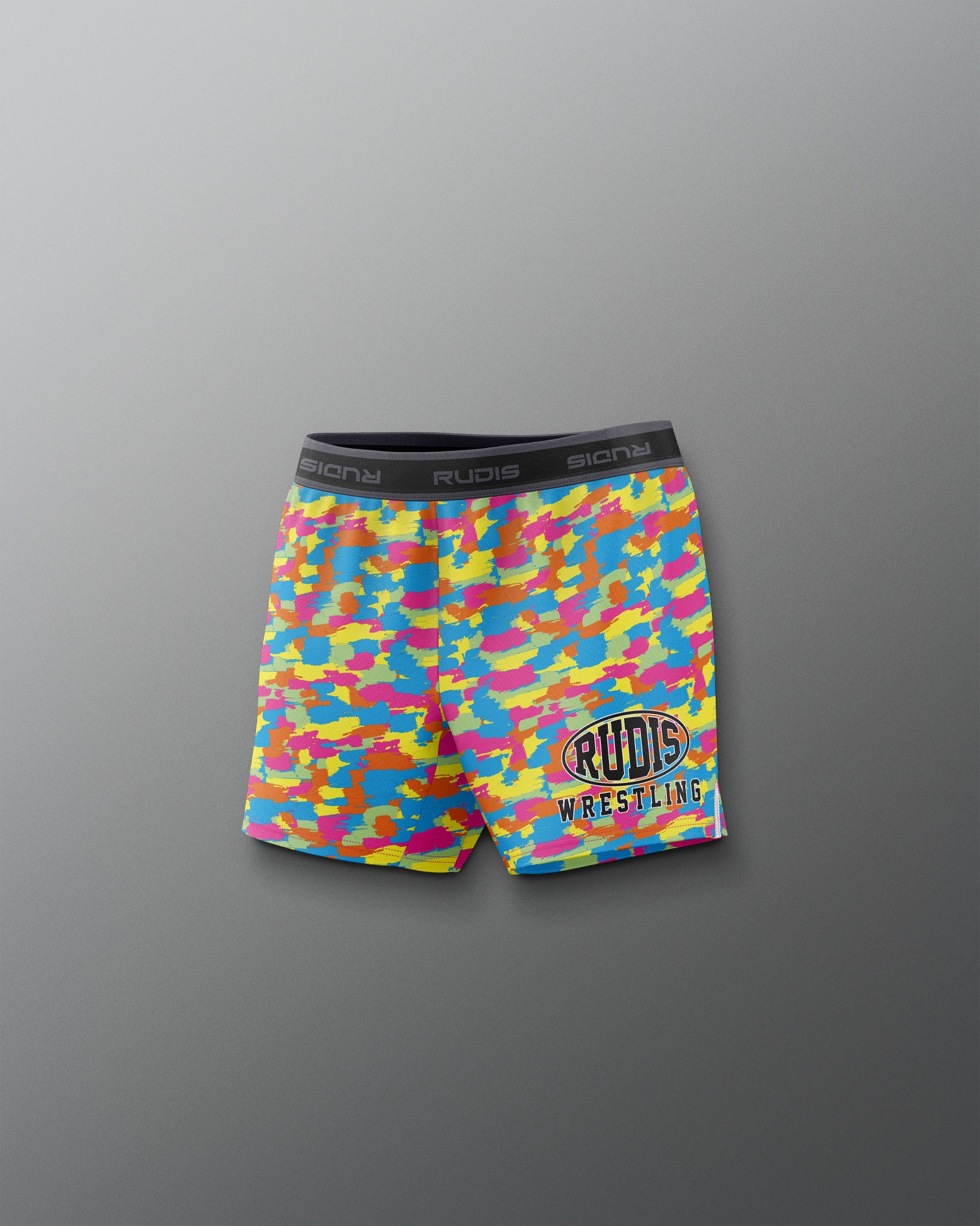 Colorful camouflage wrestling shorts with 'Rudig' branding on a gray background
