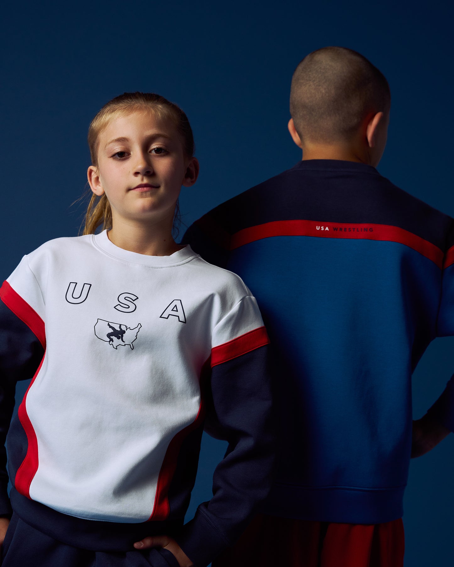 Two children wearing USA-themed athletic outfits against a dark blue background