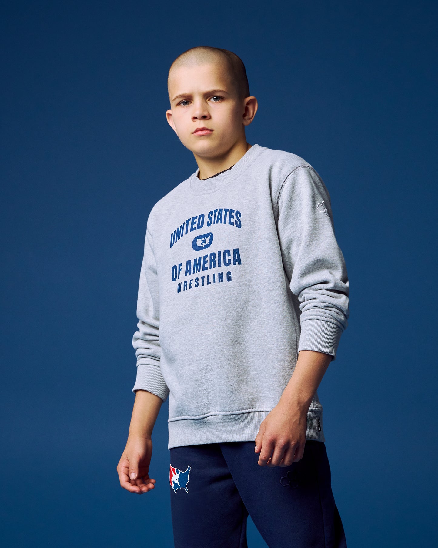 Child wearing a gray sweatshirt with 'United States of America Wrestling' text on a blue background