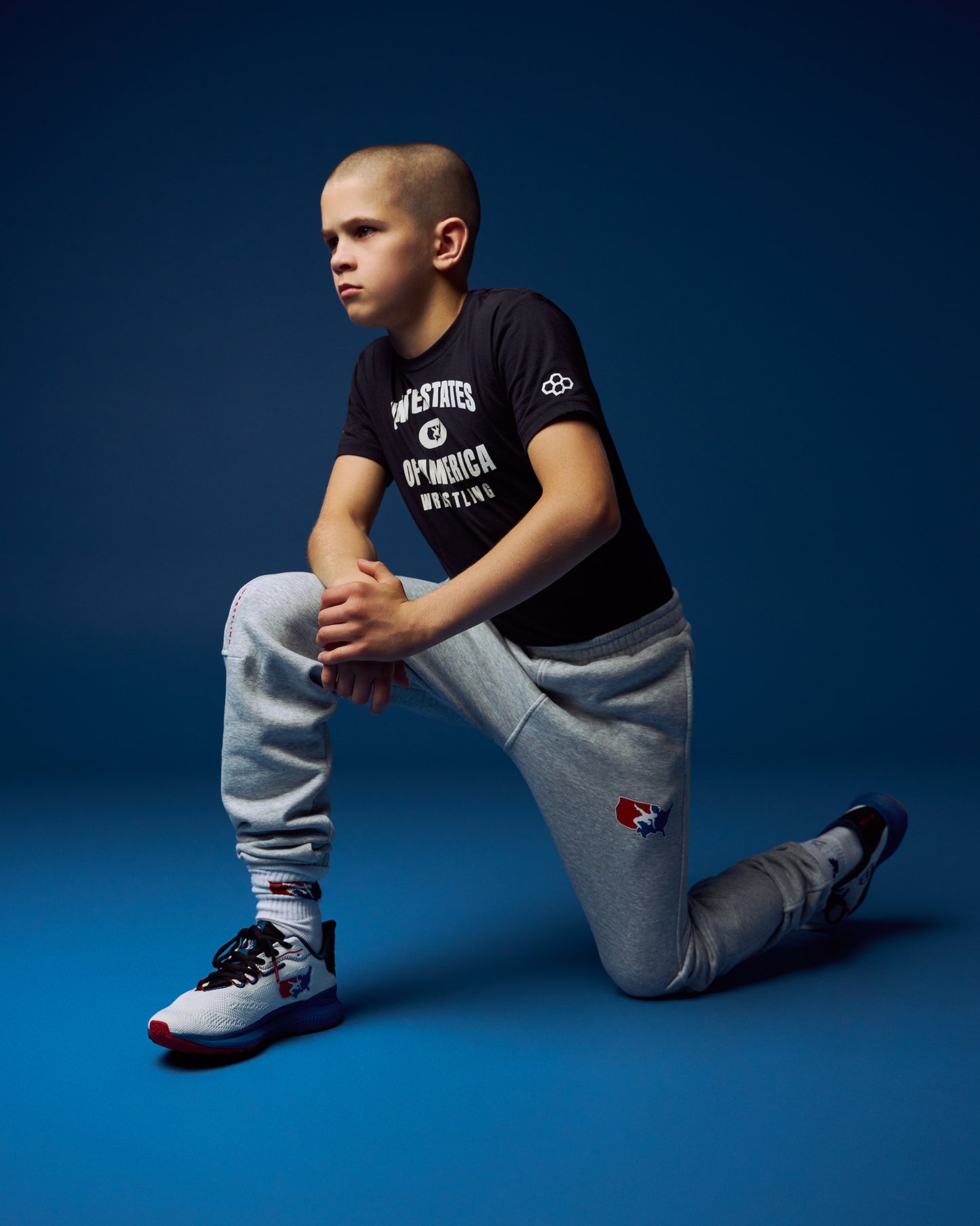 Child wearing a black t-shirt and gray pants on a blue background