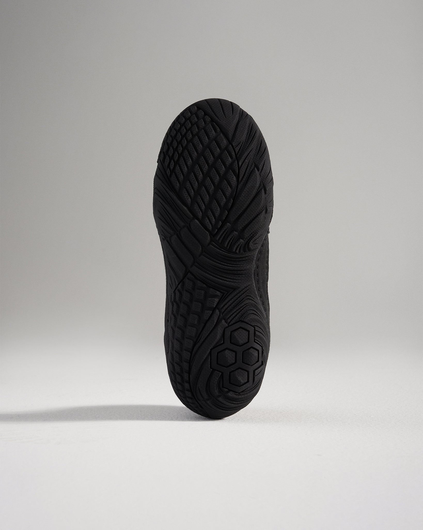 A close-up view of the textured sole of a black athletic shoe showcasing intricate tread patterns designed for grip and durability