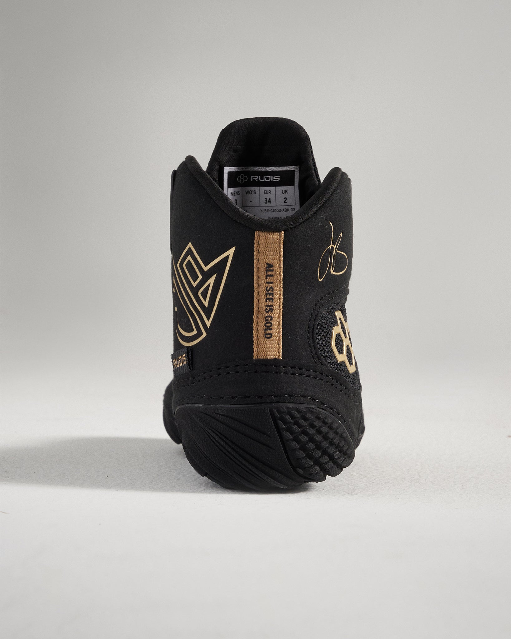 A sleek black wrestling shoe featuring a high-top design distinctive gold branding and a textured sole for optimal grip
