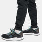 A close-up view of a person wearing sleek black athletic shoes with mint green accents paired with dark jogger pants