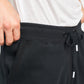 Close-up of a persons hand adjusting the waistband of black sweatpants showcasing a drawstring and pocket area