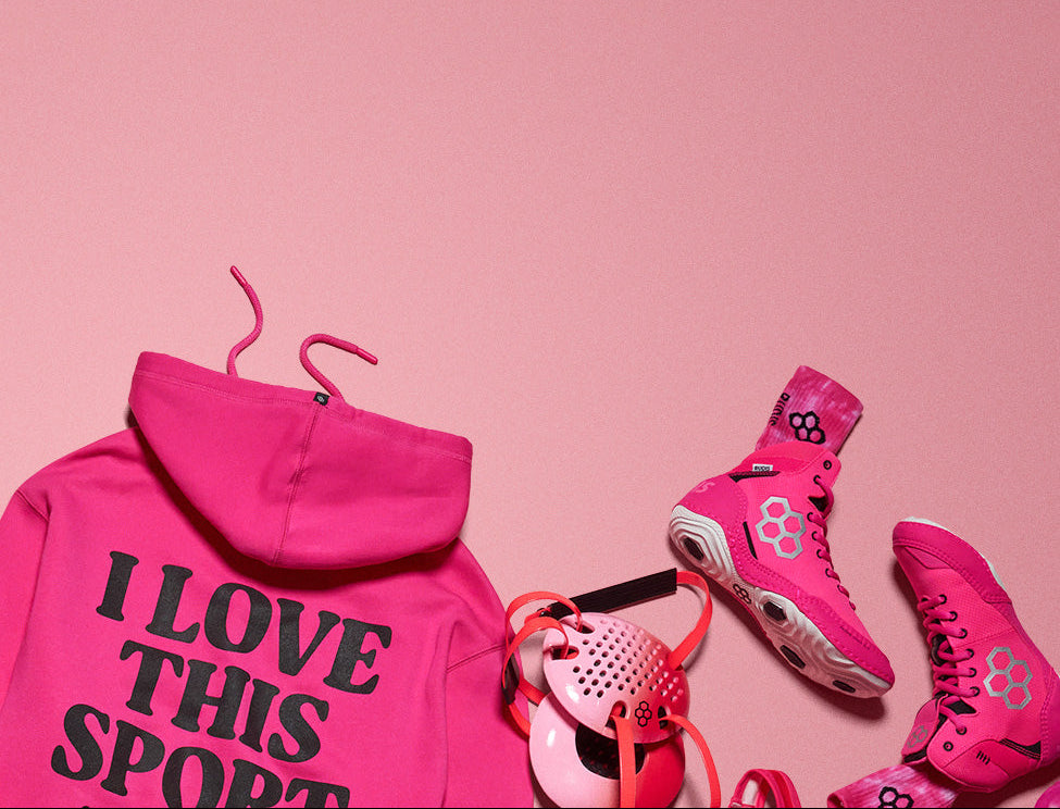 Collection of Pink RUDIS Apparel, pink RUDIS wrestling shoes and pink RUDIS wrestling gear on a pink background.