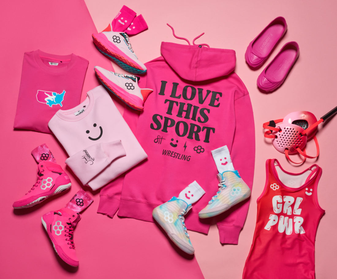 Collection of Pink RUDIS Apparel, pink RUDIS wrestling shoes and pink RUDIS wrestling gear on a two toned pink background.