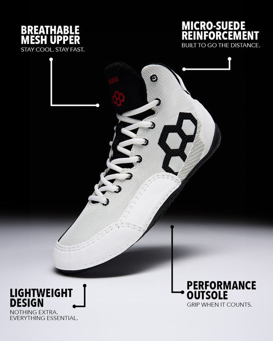 A high-top athletic wrestling shoe shown on a black-to-white gradient background with callout text and arrows explaining features: engineered mesh upper, micro-suede reinforcement, lightweight design, and performance outsole.