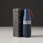 A modern insulated water bottle in navy blue accompanied by its sleek black packaging featuring the brand name RUDIS prominently displayed