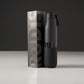 A sleek black water bottle with a textured grip standing next to its packaging featuring bold typography that reads RUDIS