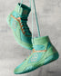A pair of vibrant mint green wrestling shoes suspended by laces against a textured background showcasing a unique design with geometric accents