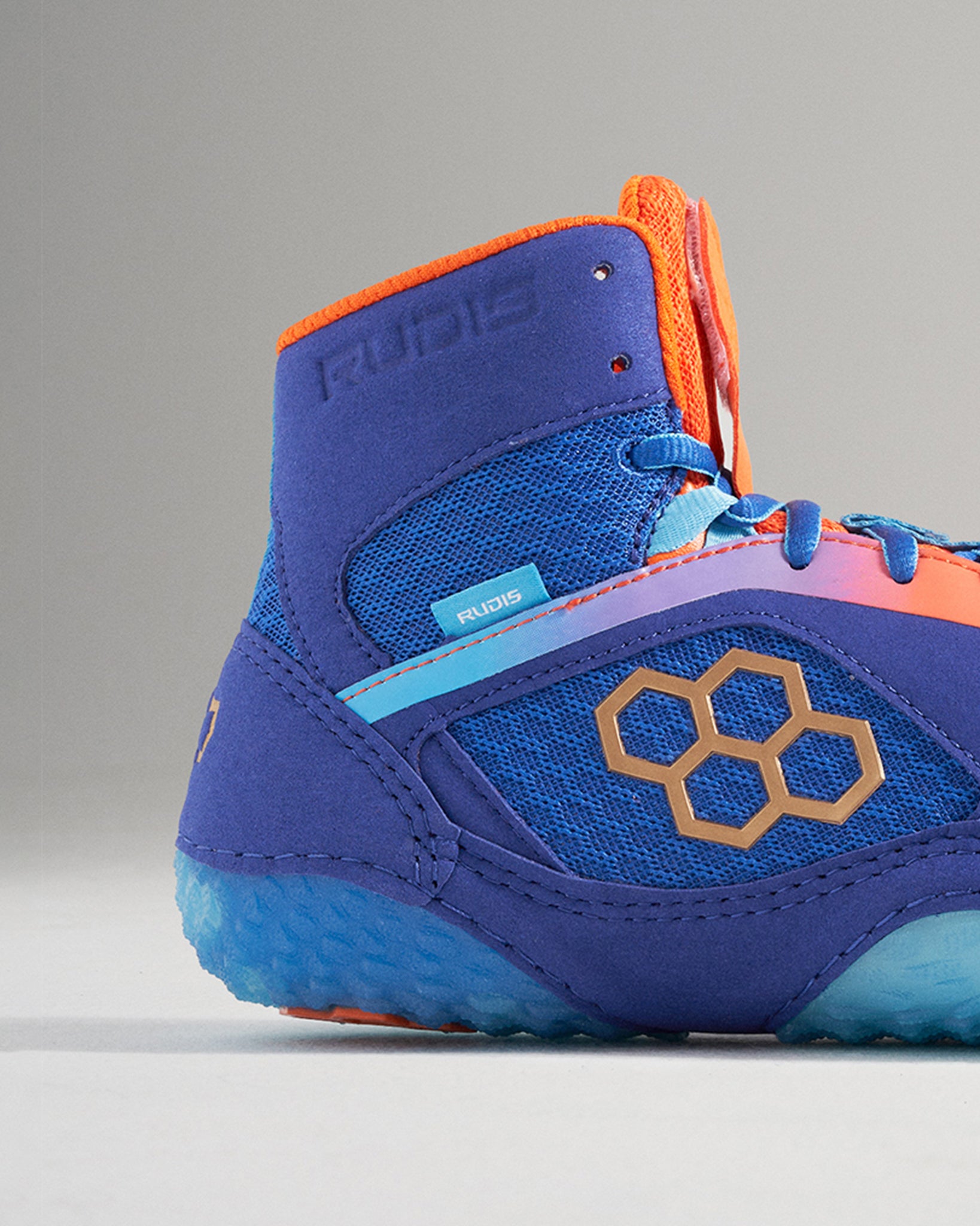 A vibrant blue wrestling shoe featuring orange and teal accents designed for optimal grip and support