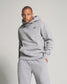 A stylish man poses confidently in a light gray hoodie and matching sweatpants showcasing a casual and contemporary fashion aesthetic