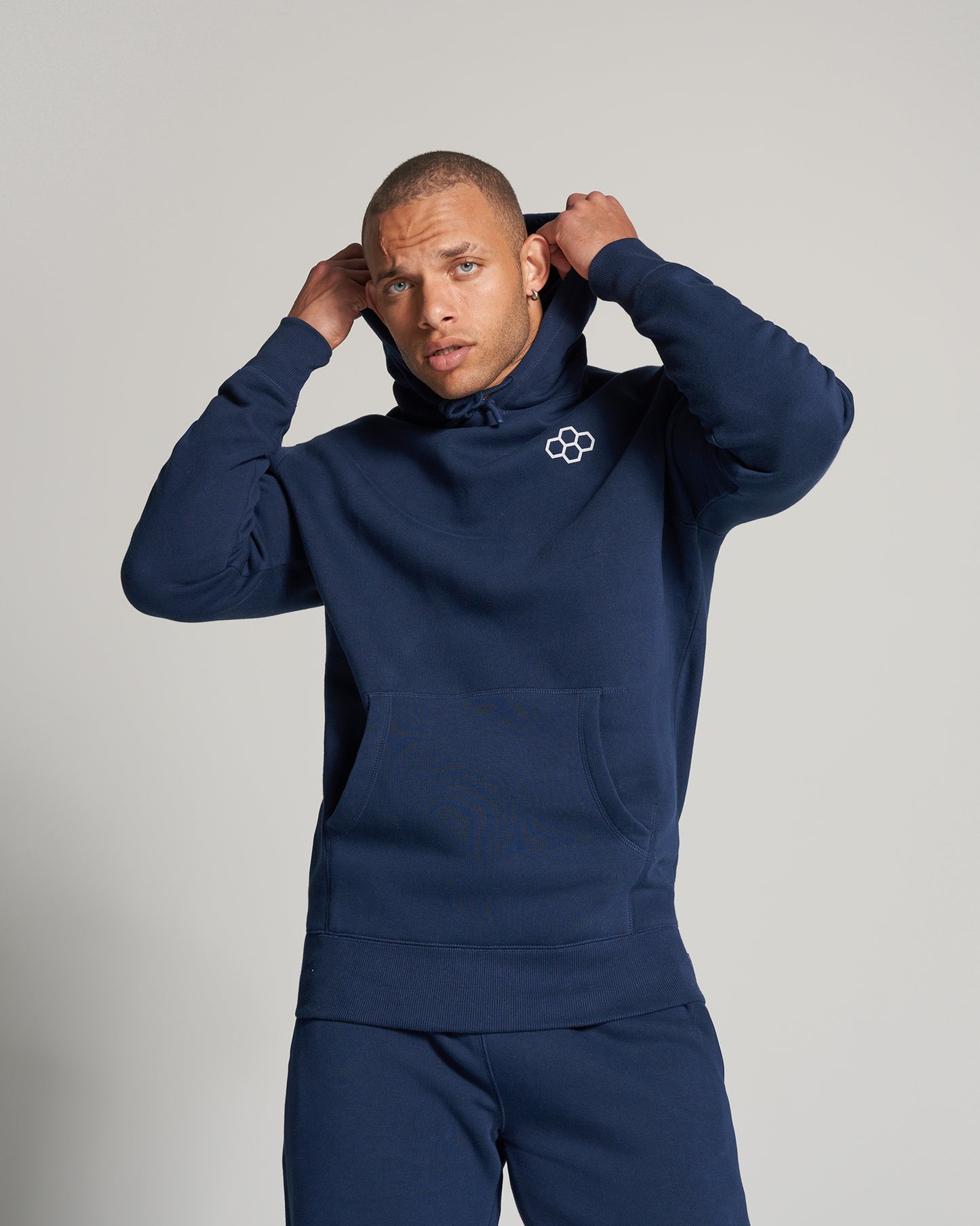 A young man in a navy blue hoodie adjusted his hood showcasing a stylish and casual look