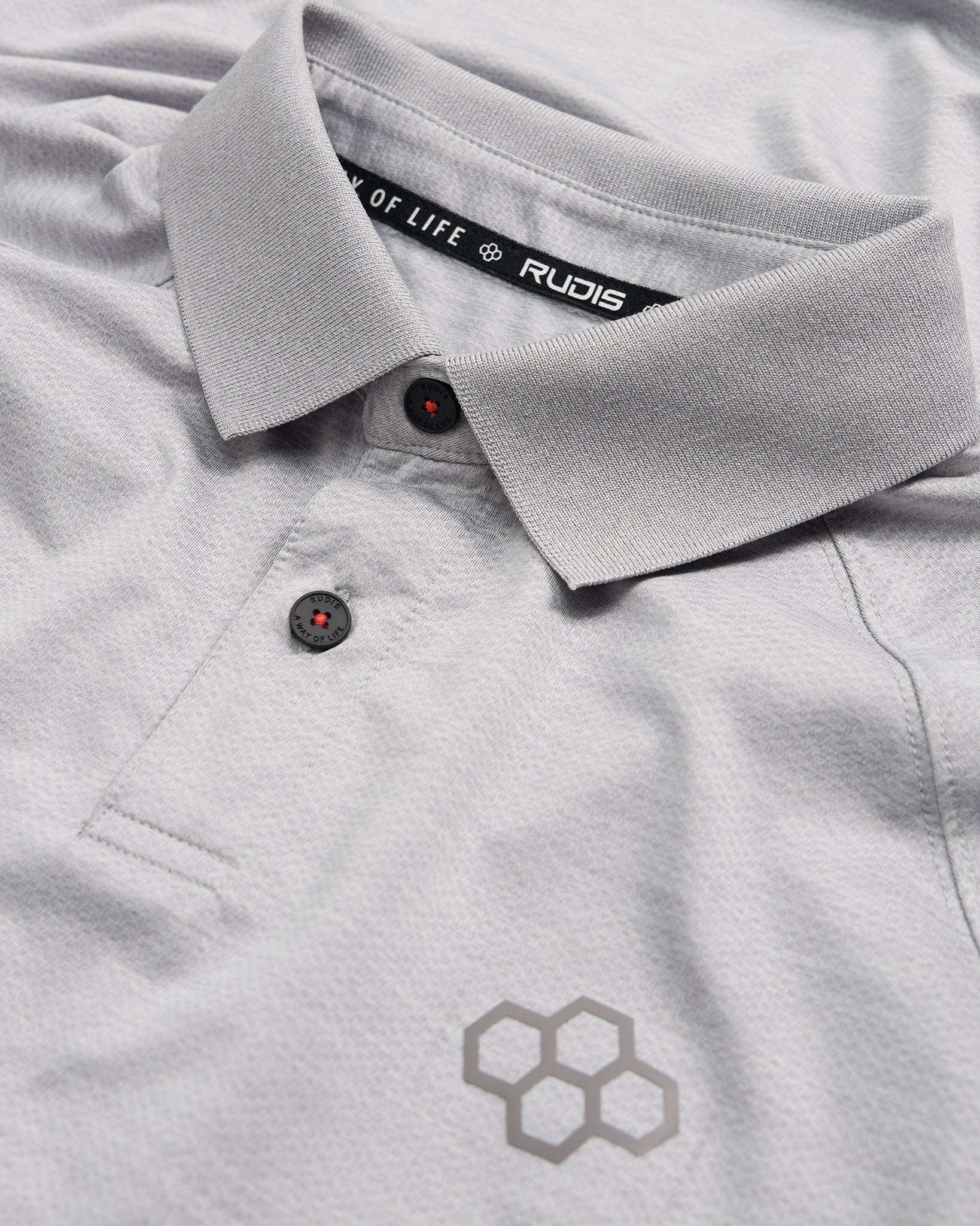 A detailed view of a light gray polo shirt featuring a stylish collar black buttons and a subtle honeycomb logo design