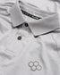 A detailed view of a light gray polo shirt featuring a stylish collar black buttons and a subtle honeycomb logo design