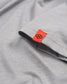 A close-up of a light gray fabric with an orange tag featuring a logo showcasing its texture and stitching details
