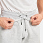 A close-up view of a person tightening the drawstring of gray sweatpants showcasing the fabric texture and the waistbands design features