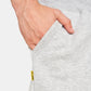 A close-up view of a persons hand resting in the pocket of light gray sweatpants featuring a small yellow brand tag