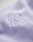 A close-up view of a soft lavender fabric featuring a stylized embroidered honeycomb design in light blue thread
