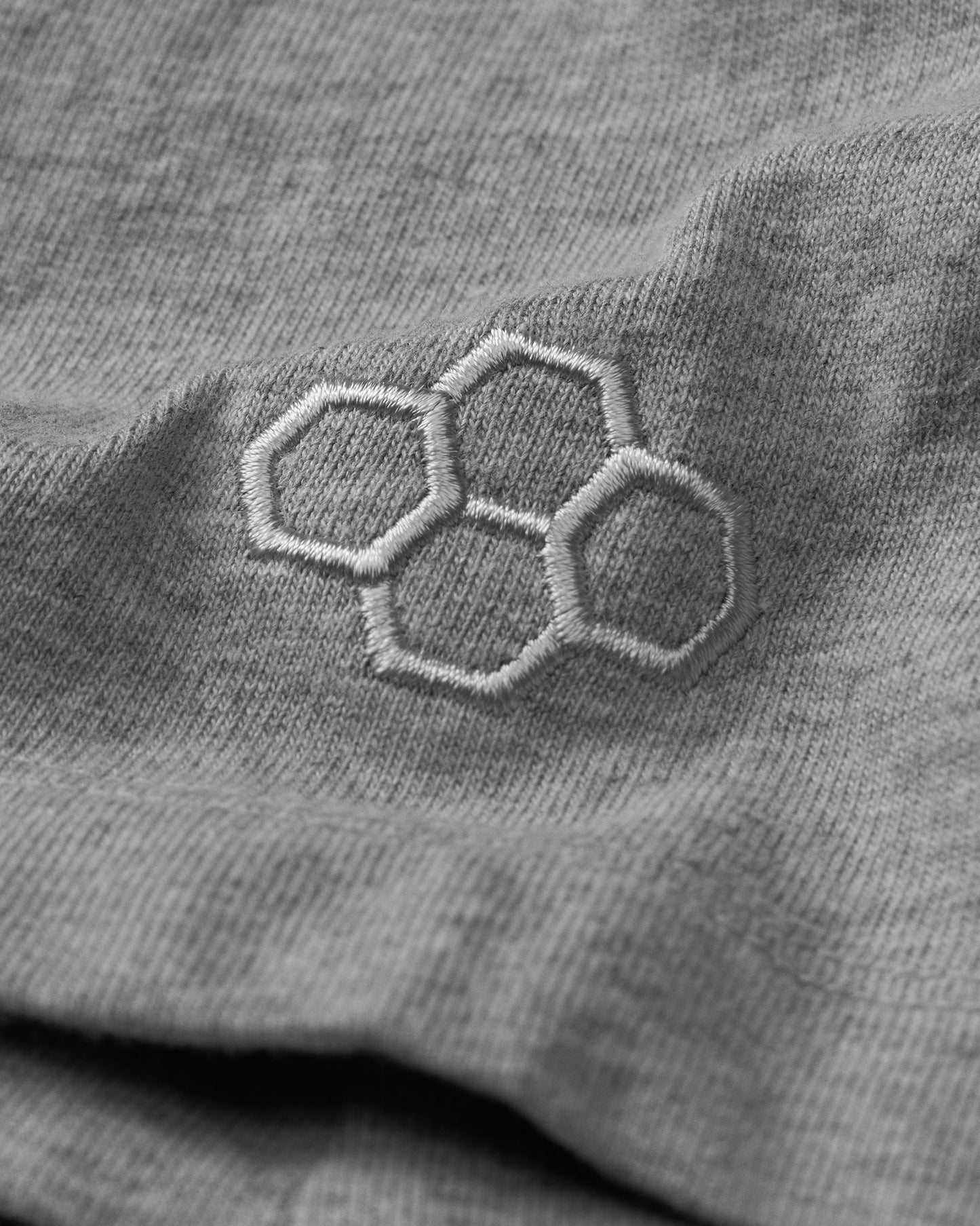 Close-up of a gray fabric with an embroidered hexagonal pattern.