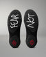 Black wrestling shoes with 'FEAR' and 'NOT' written on the soles against a gray background