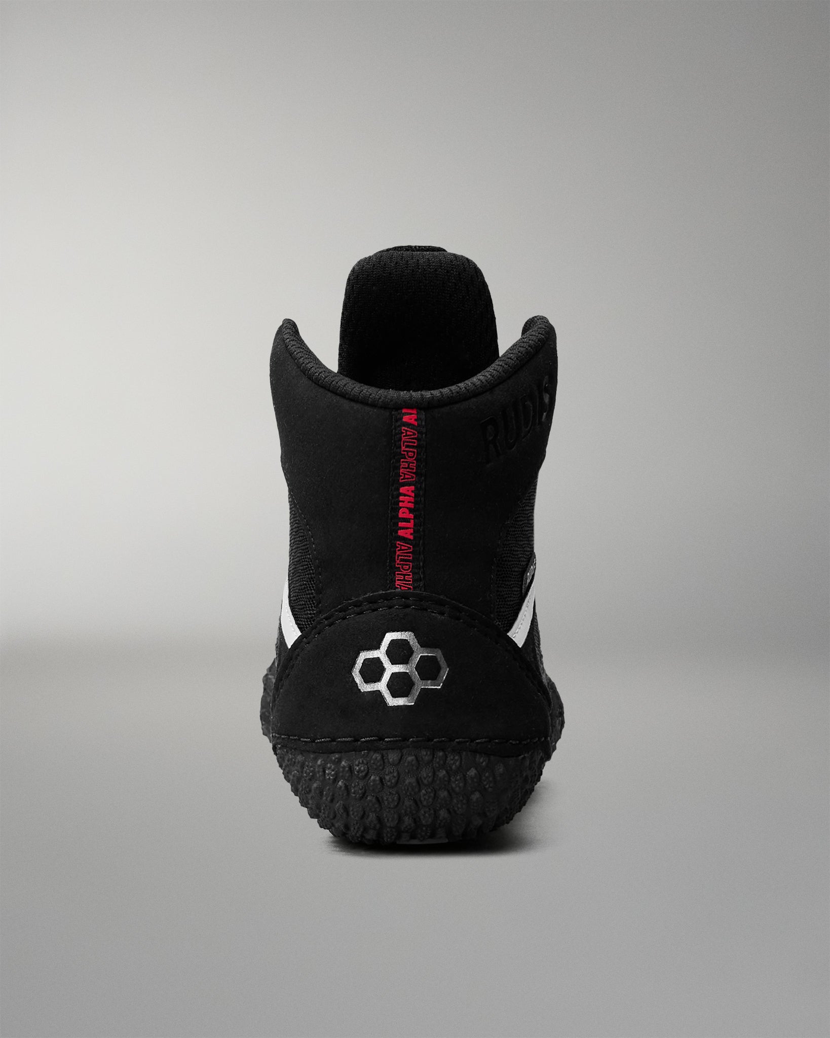 Black wrestling shoe with red text on a gray background