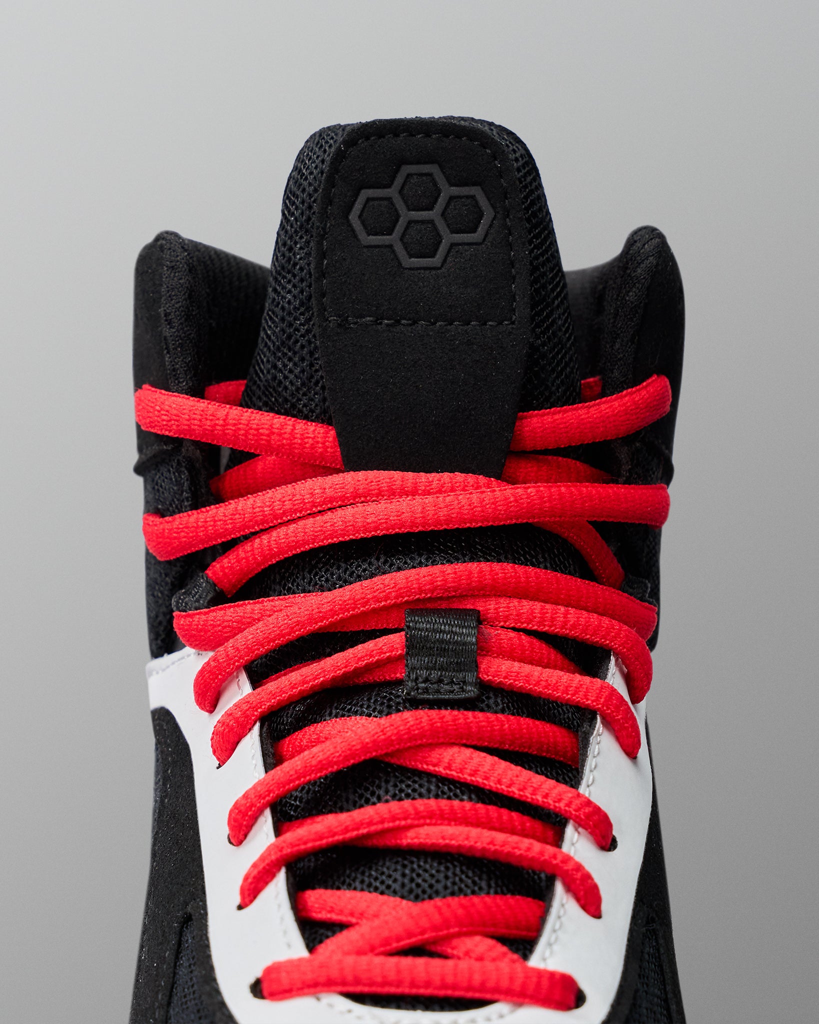 Black wrestling shoe with red laces on a gray background