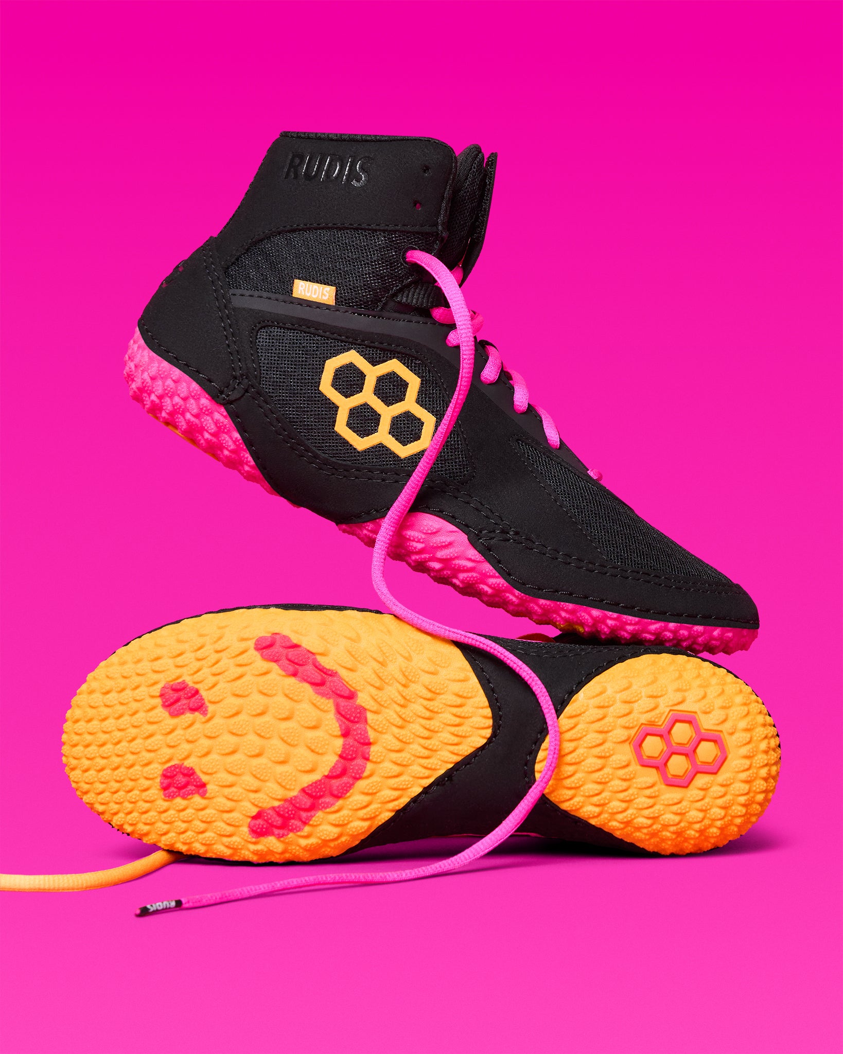 RUDIS Alpha 2.0 wrestling shoes in Happy 2.0 colorway with black, pink, and gold accents, showcasing bold style, lightweight feel, and high-traction performance
