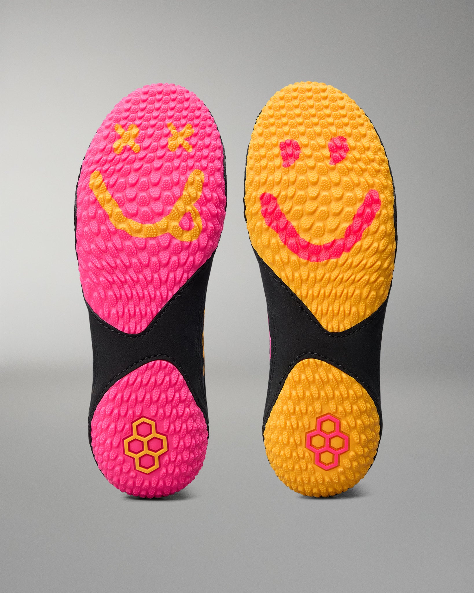 Two wrestling shoe sole with smiley face designs on a gray background