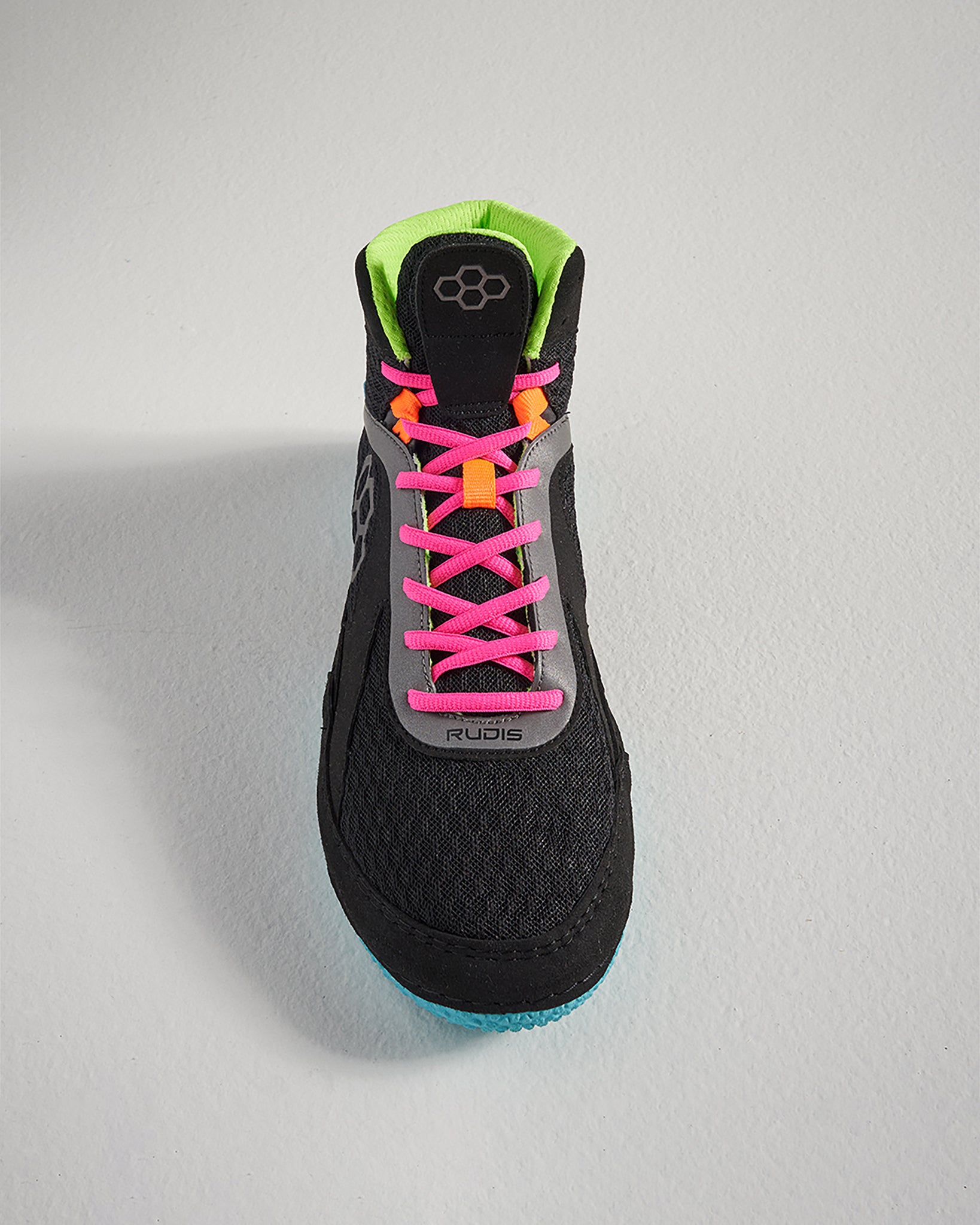 A top view of a modern black athletic shoe featuring bright pink and orange laces a green collar and a textured sole for traction