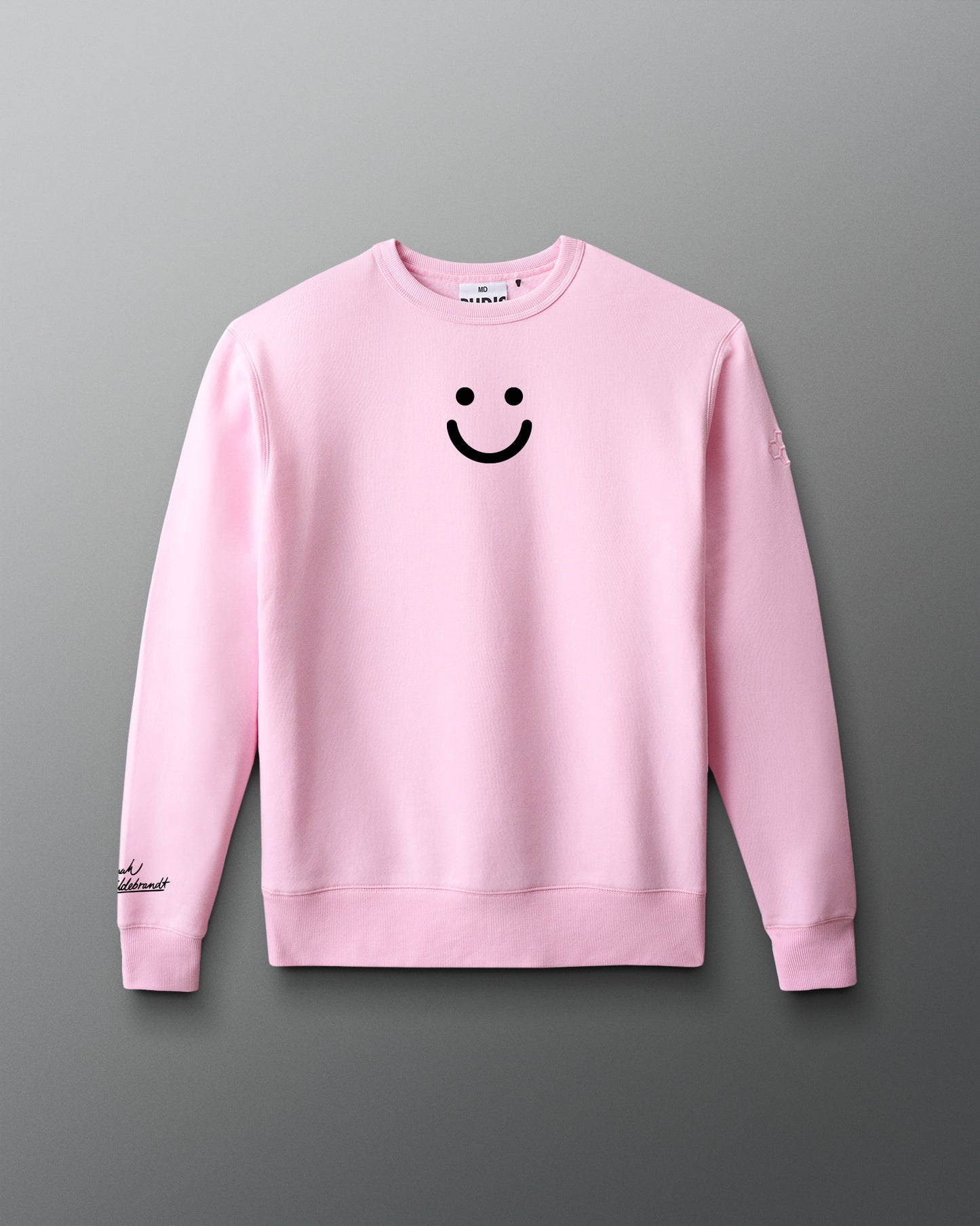 Pink sweatshirt with a smiley face design on a gray background