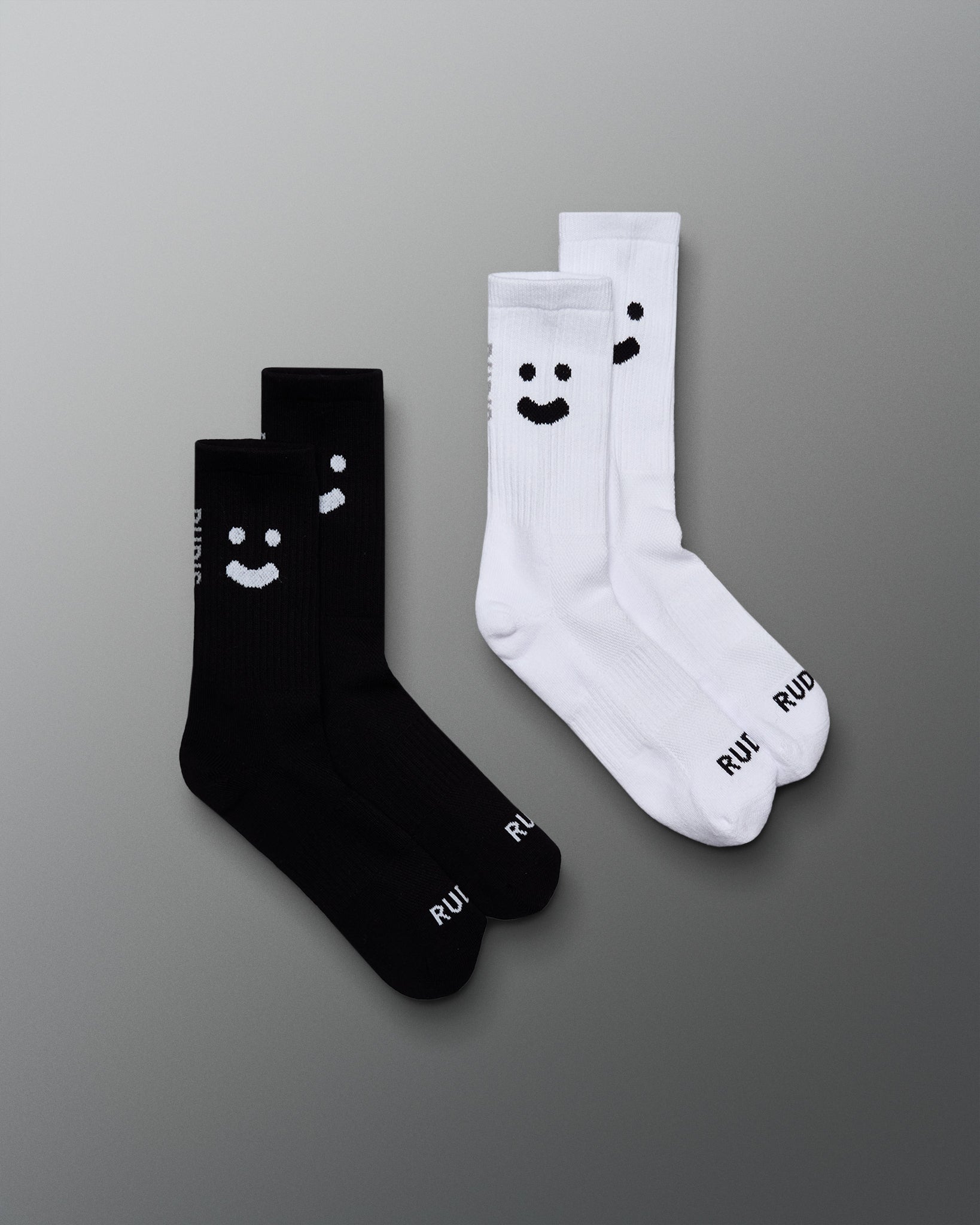 Two pairs of socks, one black and one white, with smiley face designs on a gray background.