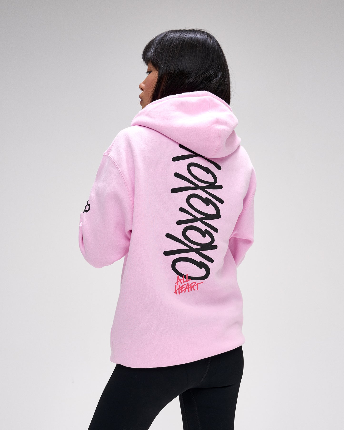 Person wearing a pink hoodie with text on the back against a gray background