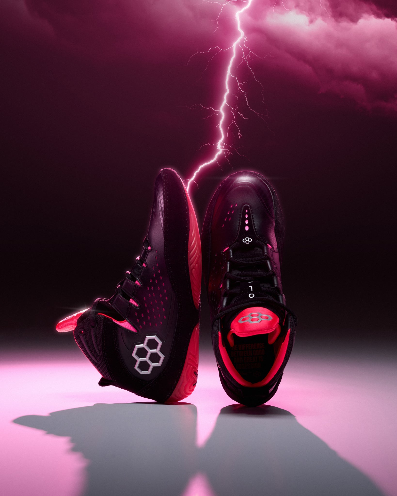 Black and pink wrestling shoes with a lightning bolt effect on a dark background