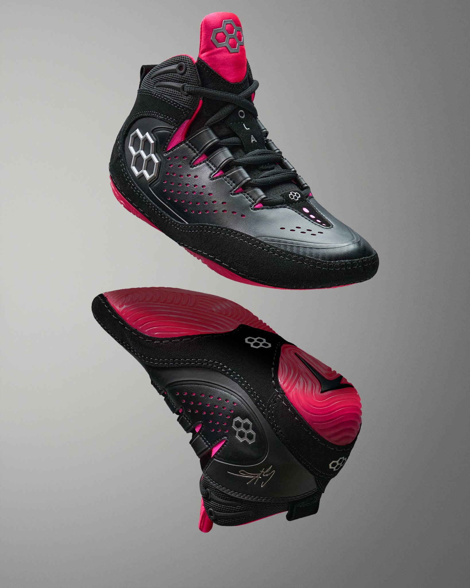 Black and pink wrestling shoes on a gray background