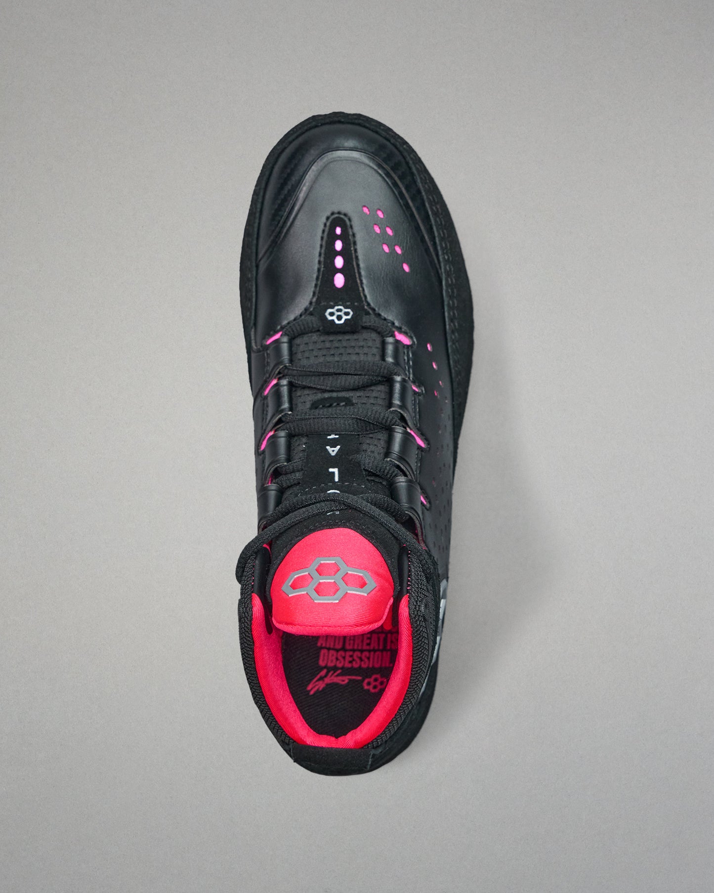 Black wrestling shoe with pink interior on a gray background