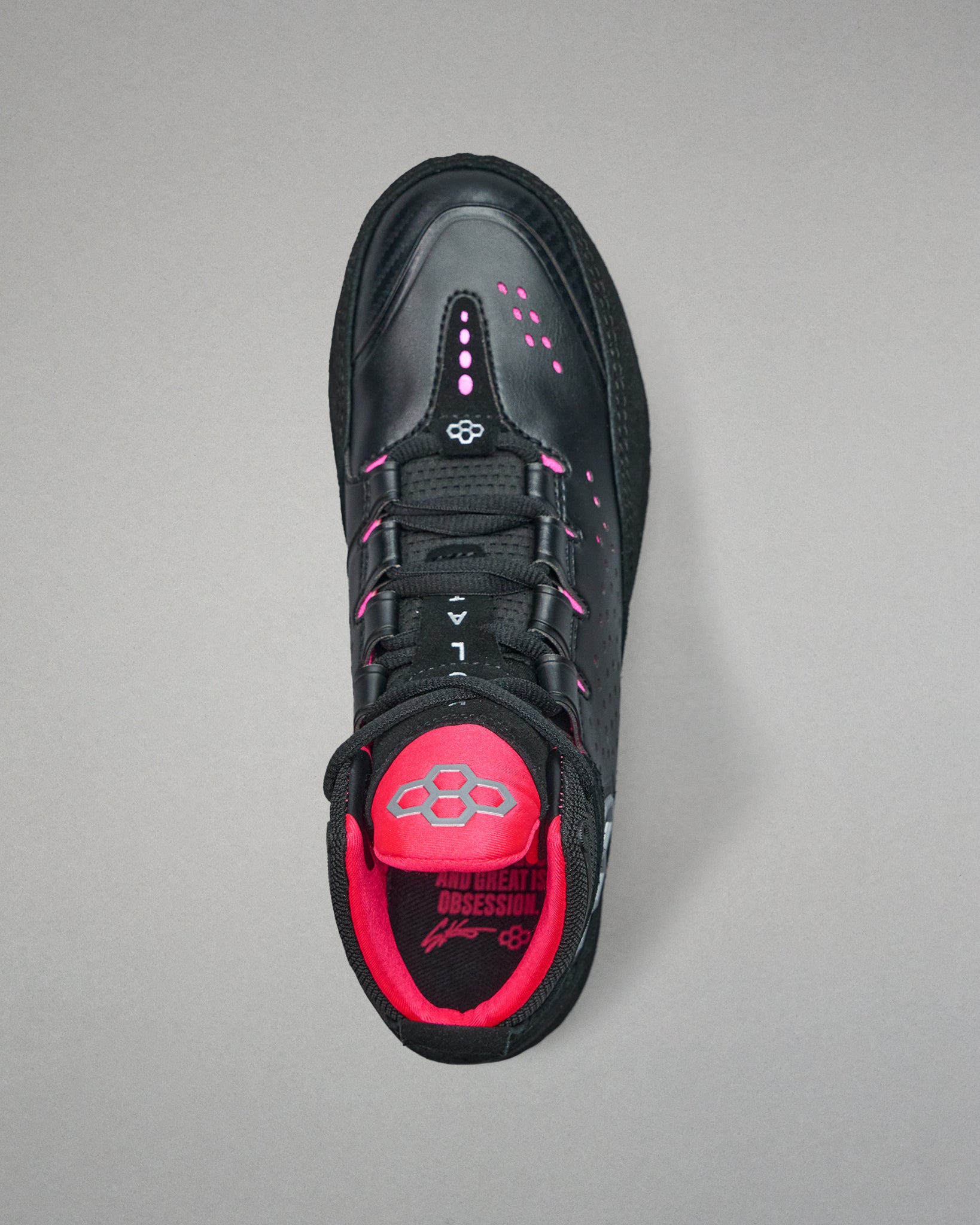 Black wrestling shoe with pink interior on a gray background