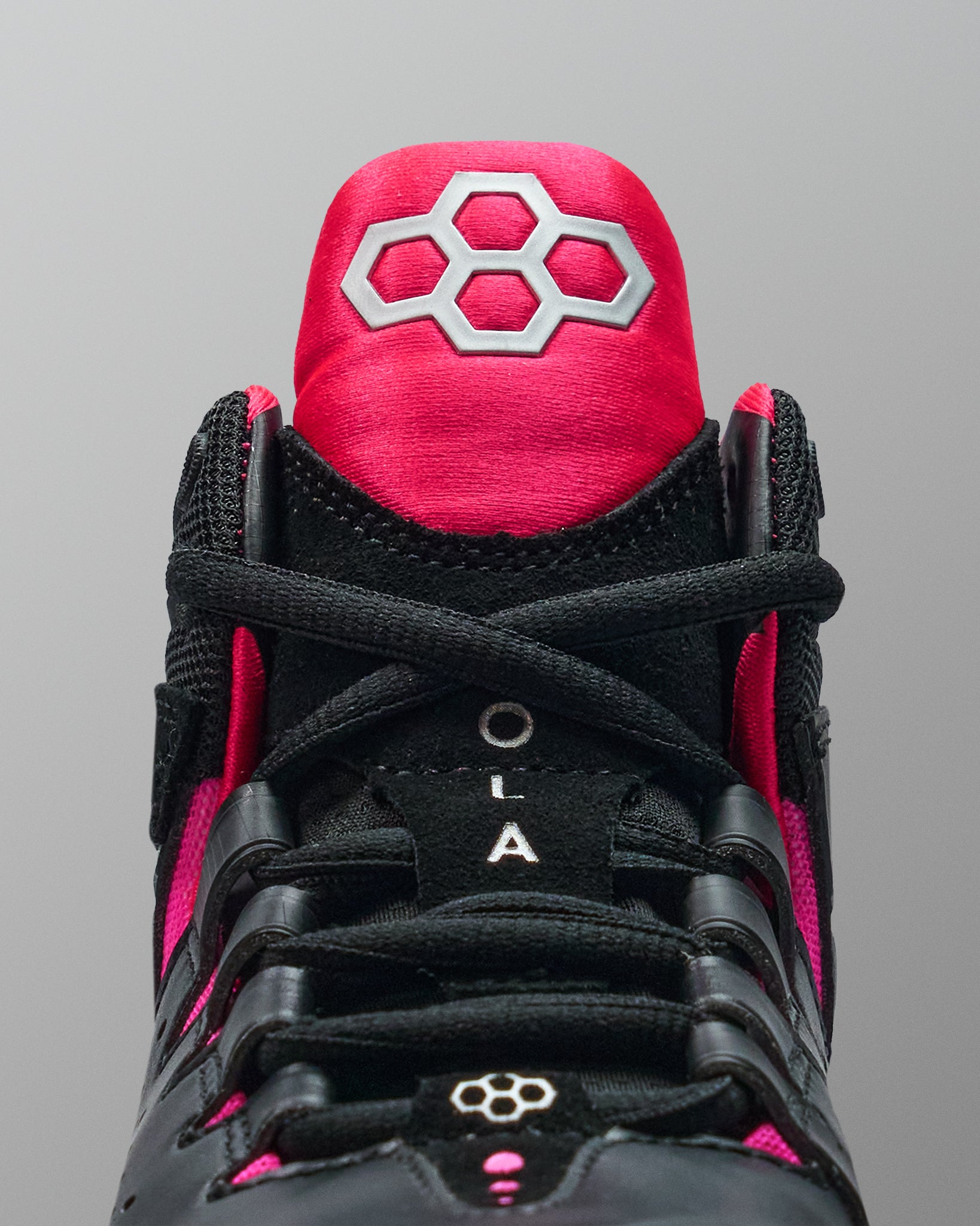 Black and pink wrestling shoe with a prominent RUDIS brand logo on a gray background
