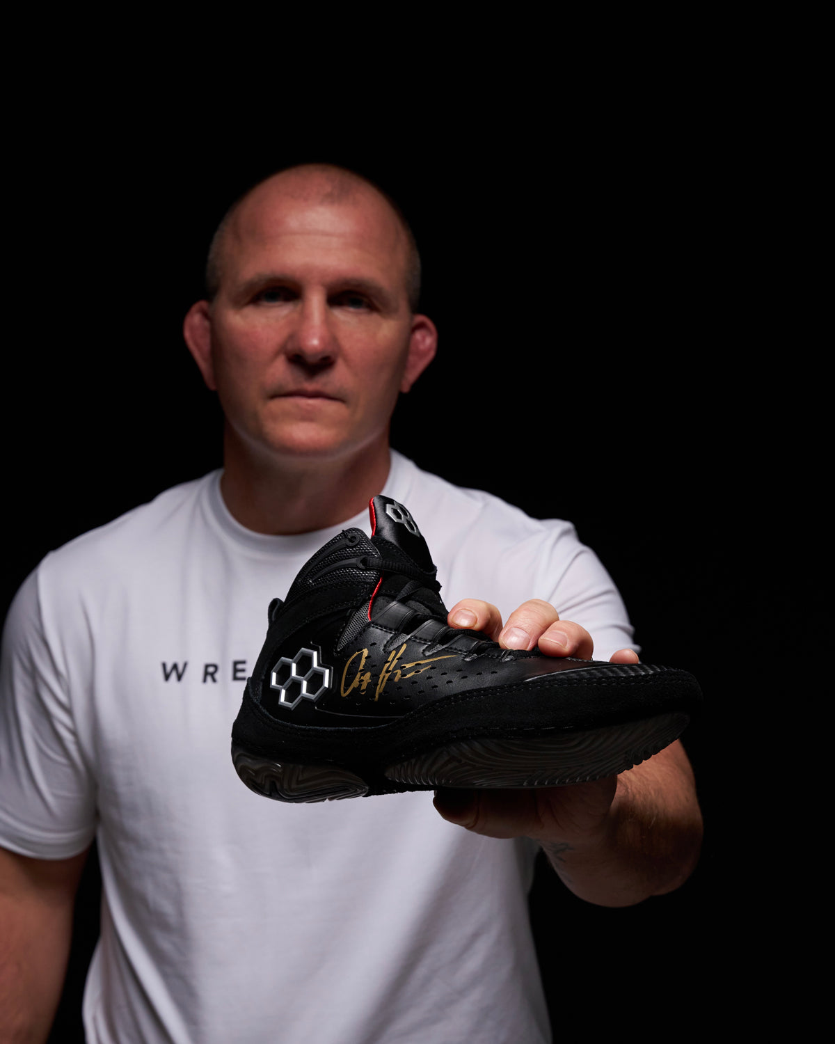 Cary Kolat holding signed RUDIS Kolat wrestling shoes - Legacy, a core colorway, highlighting elite performance design and athlete collaboration