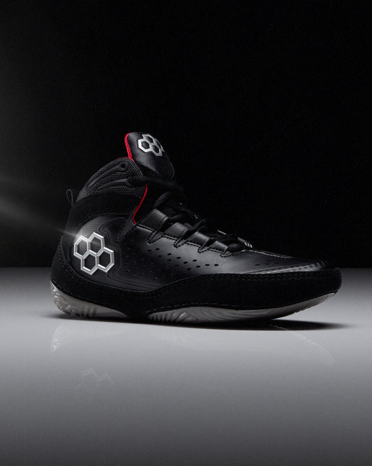 Black wrestling shoe with 'RUDIS' brand logo on a dark background