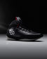 Black wrestling shoe with 'RUDIS' brand logo on a dark background