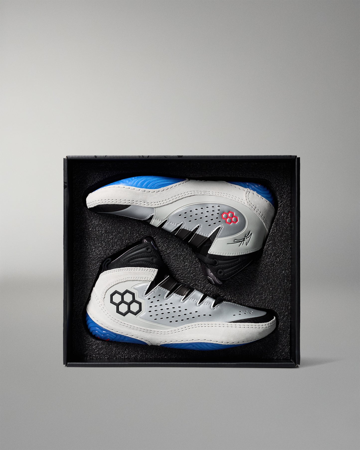 White and blue wrestling shoes in a black box on a gray background