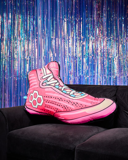 Pink wrestling shoe pillow with RUDIS logo on a black couch with a colorful, starry background