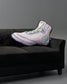 Sneaker-shaped pillow on a black couch against a gray background