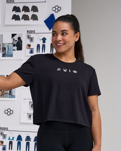 Person wearing a black t-shirt with brand logos in front of a whiteboard with design sketches.