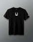 A black short-sleeve crewneck t-shirt featuring a white minimalist smiley face graphic on the center chest and a small white geometric logo on the left sleeve, displayed against a neutral gray background.