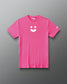 A bright pink short-sleeve crewneck t-shirt with a white minimalist smiley face graphic on the center chest and a small white logo on the left sleeve, displayed against a dark gray gradient background.