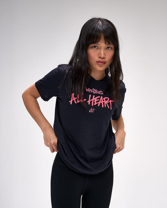 Person wearing a black t-shirt with pink text on a plain background